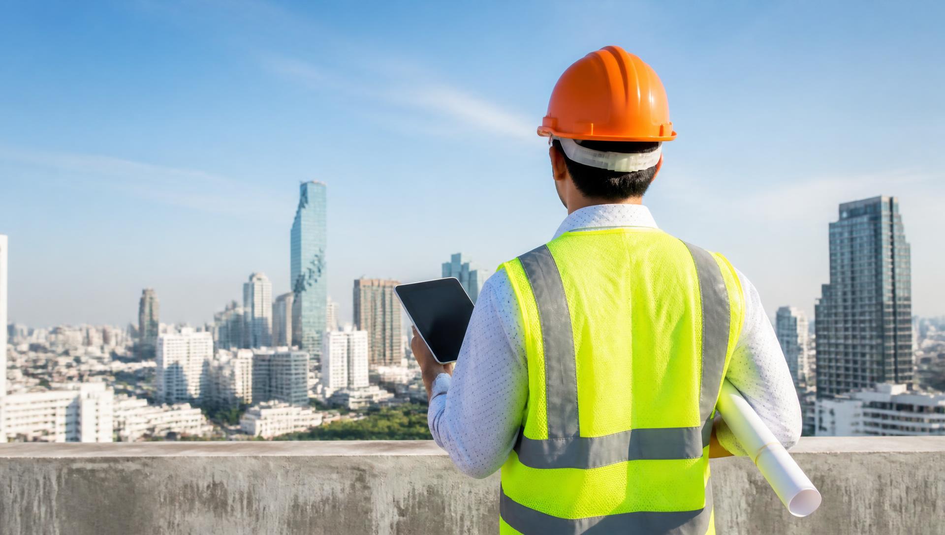 Construction supervisor reviewing project plans on a rooftop above a city skyline